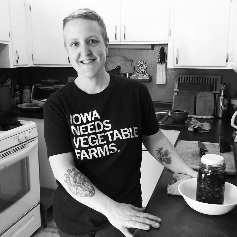 Katy Meyerof Trumpet Blossom Café poses at home in an "Iowa Needs Vegetable Farmers" tee